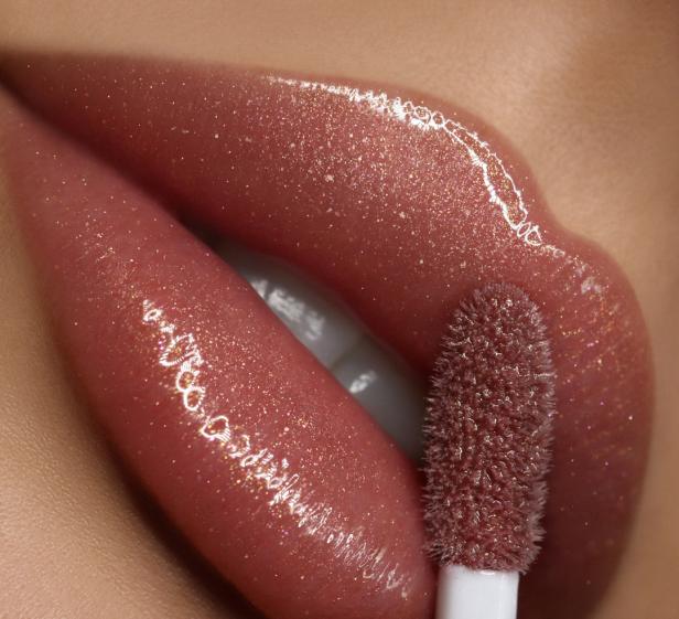 Nahaufnahme von glänzenden Lippen mit einem Applikator für Lipgloss.