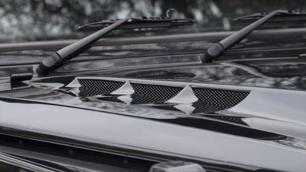 Detailansicht der Motorhaube eines schwarzen Geländewagens mit Lüftungsschlitzen und Scheibenwischern.