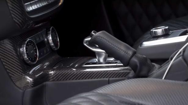 Detailaufnahme des Innenraums eines Autos mit Kohlefaser-Akzenten und Ledersitzen.