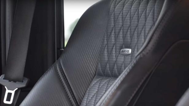 Detailaufnahme eines schwarzen AMG-Autositzes mit perforiertem Leder und Karbonfaser-Akzenten.