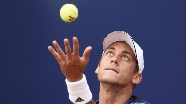 Ein Tennisspieler wirft einen Tennisball in die Luft, um aufzuschlagen.