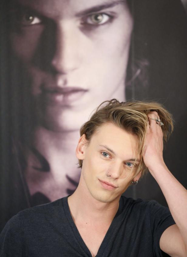 Jamie Campbell Bower posiert vor einem Porträt von sich selbst.