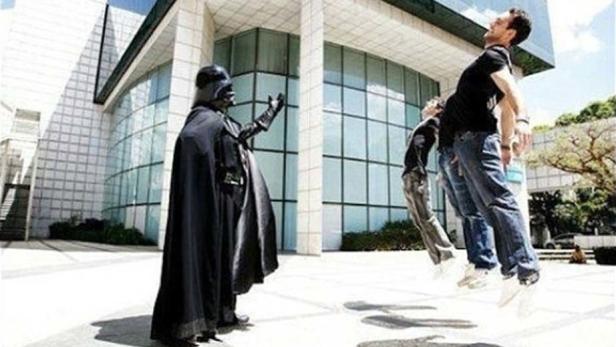 Darth Vader scheint seine Macht auf drei schwebende Personen vor einem Gebäude anzuwenden.