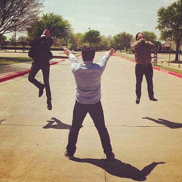 Drei Männer springen auf einer Straße in die Luft.