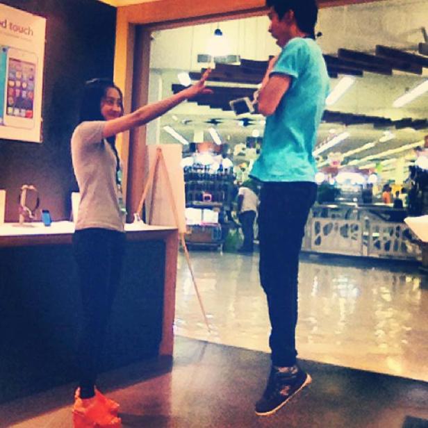 Eine Frau streckt ihre Hand aus, um die Größe eines springenden Mannes zu messen.