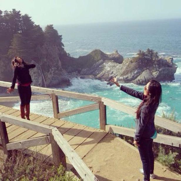 Zwei Frauen genießen die Aussicht von einer Holzbrücke auf das türkisfarbene Meer.