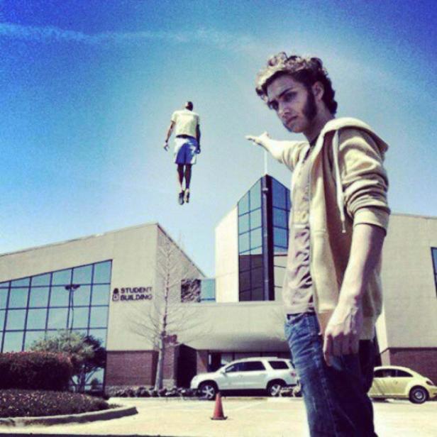 Ein Mann deutet auf eine Person, die vor einem Studentenwohnheim in der Luft schwebt.