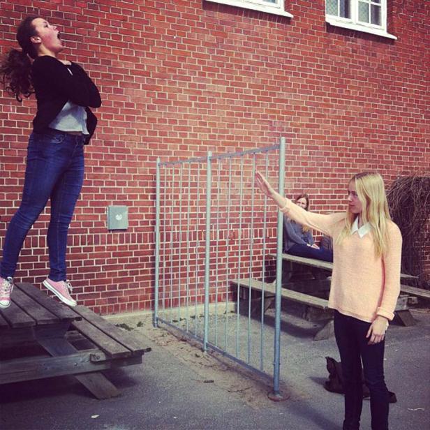 Eine junge Frau steht auf einem Tisch, während eine andere ihre Hand ausstreckt.