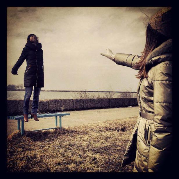 Eine Frau steht auf einer Bank, während eine andere Frau ihr die Hand entgegenstreckt.