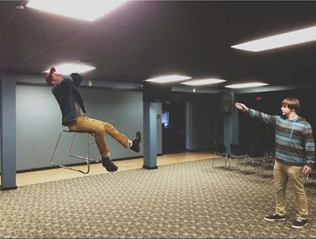 Ein Mann scheint auf einem Stuhl zu schweben, während ein anderer Mann daneben steht.