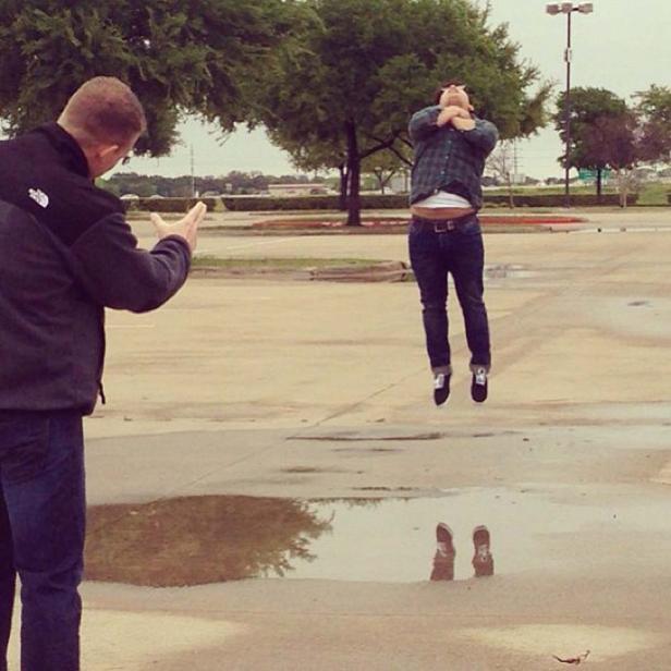 Ein Mann springt über eine Pfütze, während ein anderer Mann zusieht.