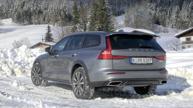 Ein grauer Volvo V60 Cross Country steht im Schnee vor einer verschneiten Landschaft.