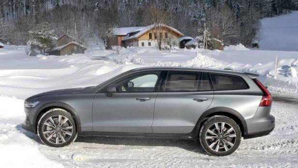 Ein grauer Volvo steht im Schnee vor einem Haus.