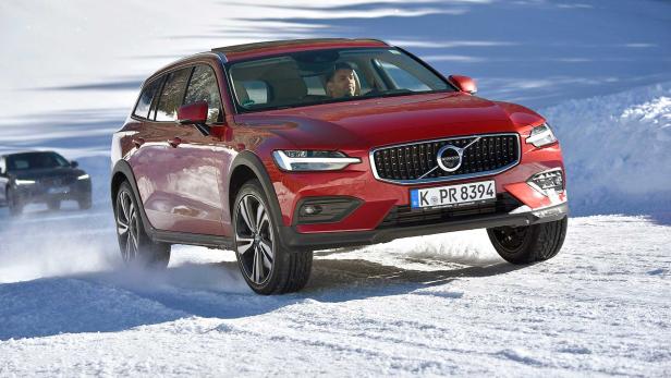 Ein roter Volvo fährt auf einer schneebedeckten Straße.