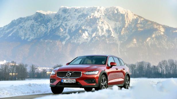 Ein roter Volvo steht vor einer verschneiten Berglandschaft.