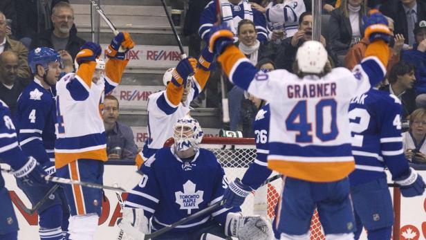 Eishockeyspieler der New York Islanders jubeln mit erhobenen Armen gegen die Toronto Maple Leafs.