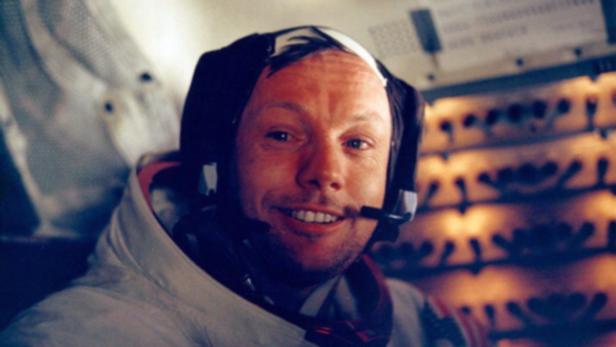 Neil Armstrong im Apollo-Raumschiff mit Headset, lächelnd.
