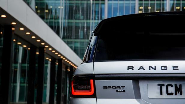 Die Rückansicht eines silbernen Range Rover Sport HST vor einem modernen Gebäude.