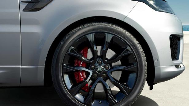 Nahaufnahme des Rads eines silbernen Range Rover mit schwarzen Felgen und roten Bremssätteln.