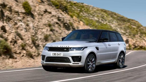 Ein silberner Range Rover fährt auf einer kurvenreichen Straße entlang.