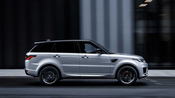 Ein silberner Range Rover fährt auf einer dunklen Straße.