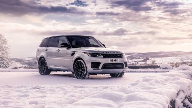 Ein silberner Range Rover Sport steht in einer verschneiten Landschaft.