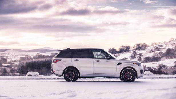 Ein silberner Range Rover Sport steht in einer verschneiten Landschaft.