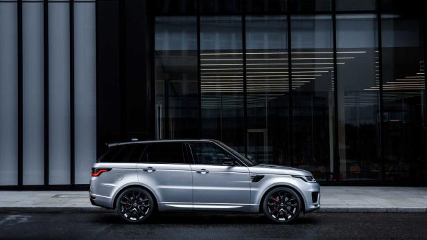 Ein silberner Range Rover Sport steht vor einem modernen Gebäude.