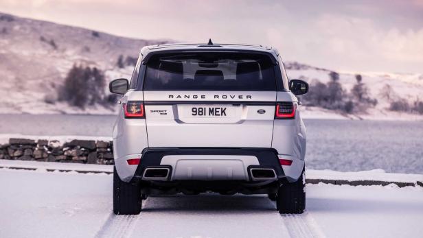 Ein silberner Range Rover Sport steht im Schnee vor einer verschneiten Landschaft.