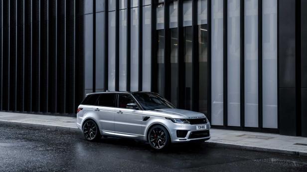 Ein silberner Range Rover Sport steht vor einem modernen Gebäude.