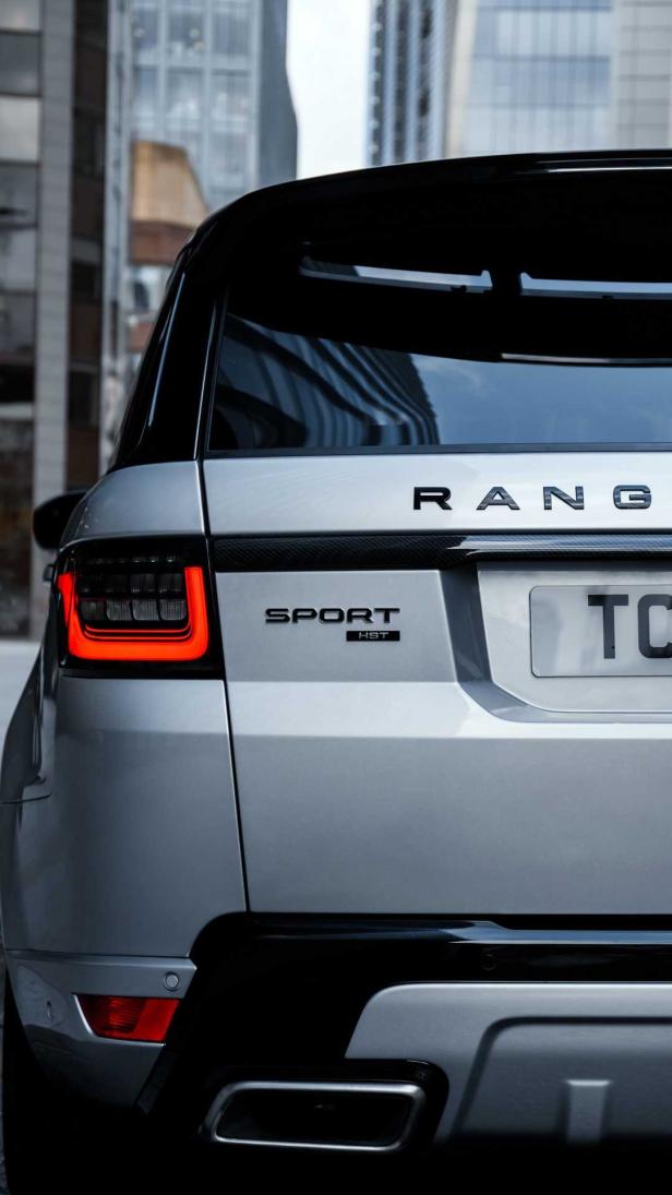 Die Rückansicht eines silbernen Range Rover Sport HST vor einem Gebäude.