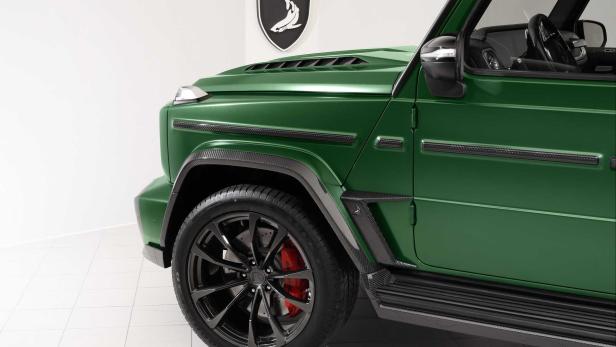 Detailansicht eines grünen Mercedes-Benz G-Klasse-Wagens mit schwarzen Felgen und roten Bremssätteln.
