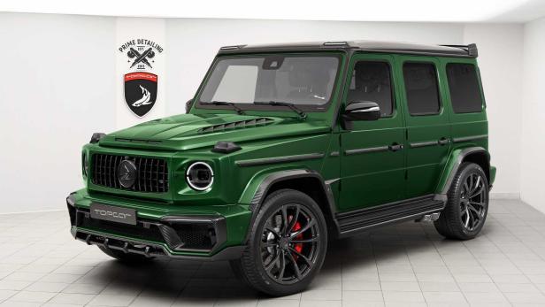 Ein grüner Mercedes-Benz G-Klasse Geländewagen mit schwarzen Akzenten steht in einem Studio.