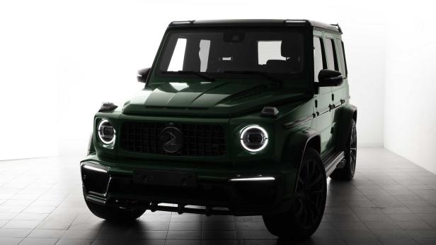 Ein grüner Mercedes-Benz G-Klasse Geländewagen mit schwarzen Akzenten steht in einem Studio.