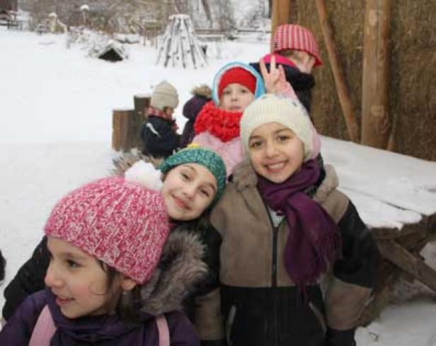 Eine Gruppe Kinder steht im Schnee und lächelt in die Kamera.