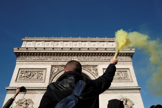A protester holds a safety flare near the Arc de Triomphe during a demonstration by the "yellow vests" movement in Paris