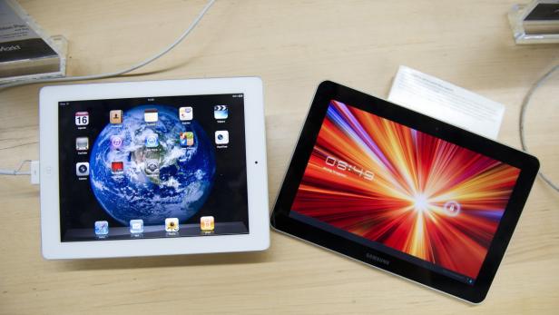 Ein iPad mit einem Bild der Erde und ein Samsung Tablet mit einem abstrakten Hintergrund liegen auf einem Tisch.
