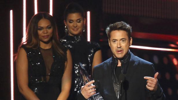 Robert Downey Jr. hält eine Auszeichnung in der Hand und spricht auf einer Bühne.