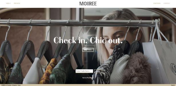 Eine Frau blickt auf eine Kleiderstange mit verschiedenen Kleidungsstücken und Einkaufstaschen.