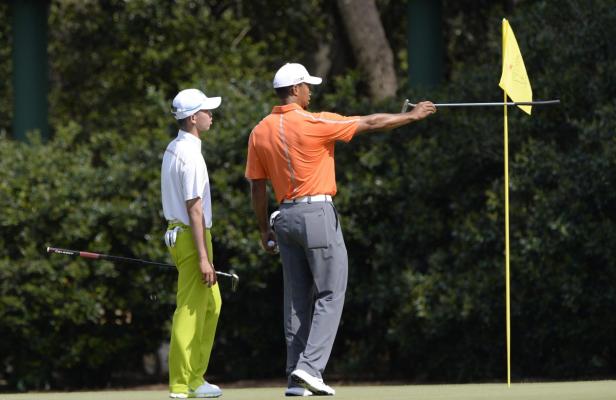 Tiger Woods zeigt einem jungen Golfer die Richtung auf dem Grün.