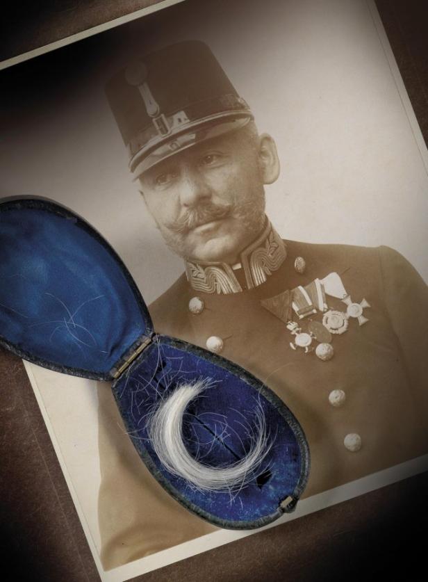 Auch eine Fotografie des kaiserlichen Leibkammerdieners Eugen Ketterl kommt unter den Hammer Ein Haarbüschel in einer Schatulle vor einem Porträt eines Mannes in Uniform.