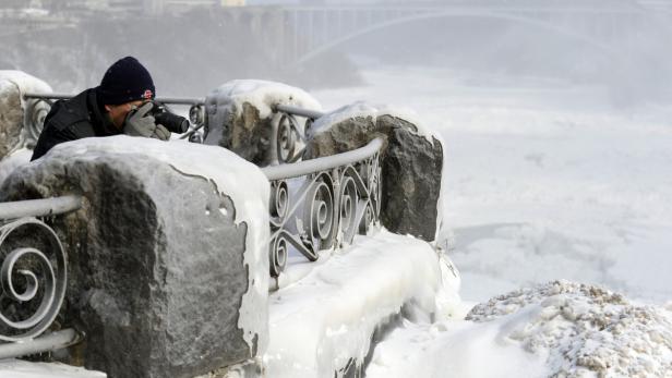 Ein Fotograf macht Aufnahmen von den schneebedeckten Niagarafällen.