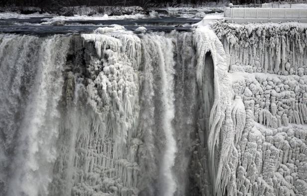 Ein gefrorener Wasserfall mit dicken Eiszapfen bedeckt die Felsen.