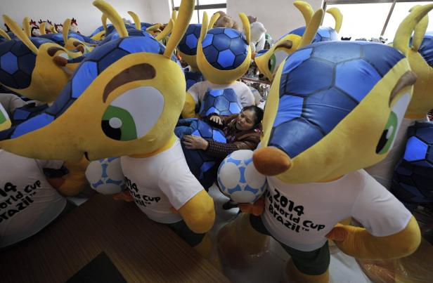 Eine Frau umarmt ein Maskottchen der FIFA Fussball-Weltmeisterschaft 2014 inmitten vieler weiterer Maskottchen.