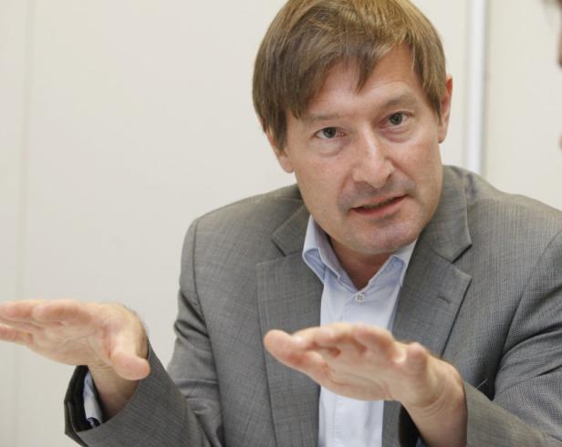 Ein Mann in einem grauen Anzug gestikuliert mit seinen Händen.