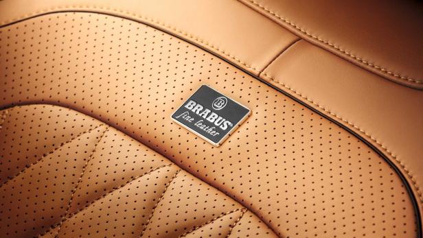 Detailaufnahme von perforiertem, hellbraunem Leder mit einem Brabus-Logo.