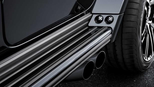 Detailansicht des Auspuffs und des Reifens eines schwarzen Autos.