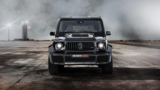 Ein schwarzer Brabus 800 Geländewagen steht auf einer Betonfläche vor einem Turm.