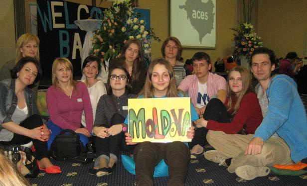 Eine Gruppe junger Leute sitzt mit einem Schild „Moldova“ auf dem Boden.