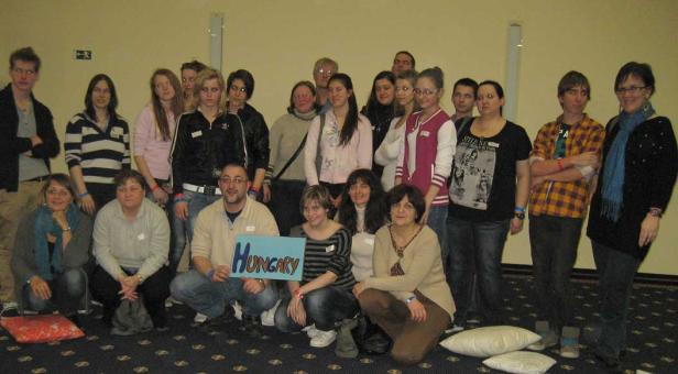 Eine Gruppe von Menschen posiert für ein Foto, einige halten ein Schild mit der Aufschrift „Hungary“.
